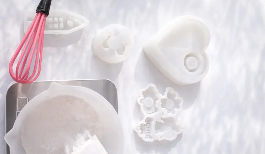 Kitchen tools and baking molds on white surface.