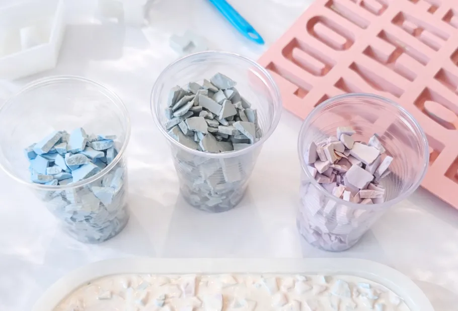 Three cups with colored clay pieces on table.