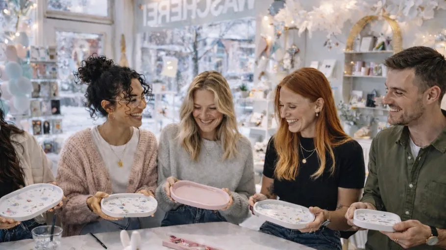 Five people happily decorating plates in a shop.