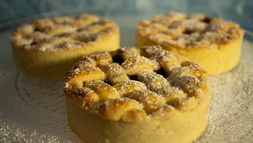 Three small lattice-topped pies with powdered sugar.