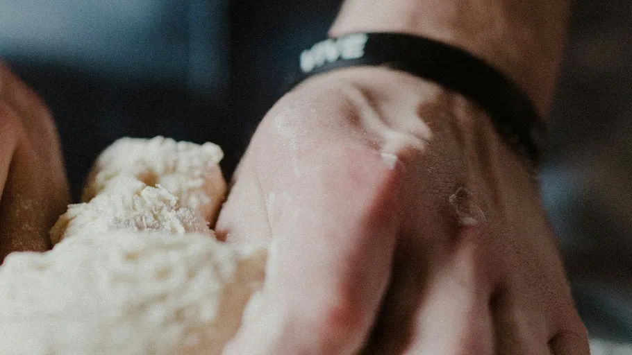 Hand kneading dough in a kitchen.