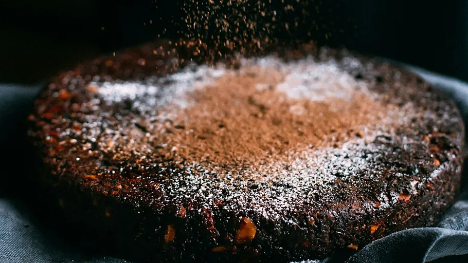 Cake with cocoa powder being sprinkled on top.