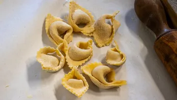 Fresh tortellini arranged on floured surface.