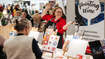 Frau zeigt Malerei bei einer Kunstveranstaltung.