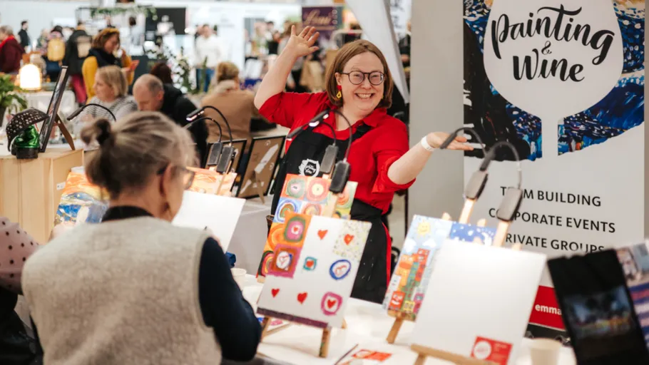 Frau zeigt Malerei bei einer Kunstveranstaltung.