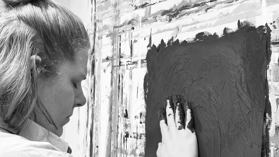 Person painting wall with dark paint, focused expression.