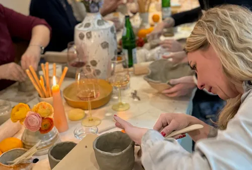 Woman sculpting clay at craft table gathering.