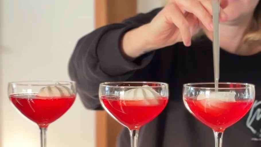 Person stirring red cocktails with shell ice.