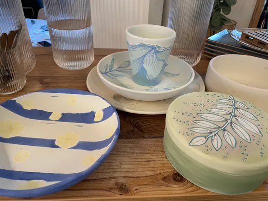 Painted pottery on wooden table outdoors.