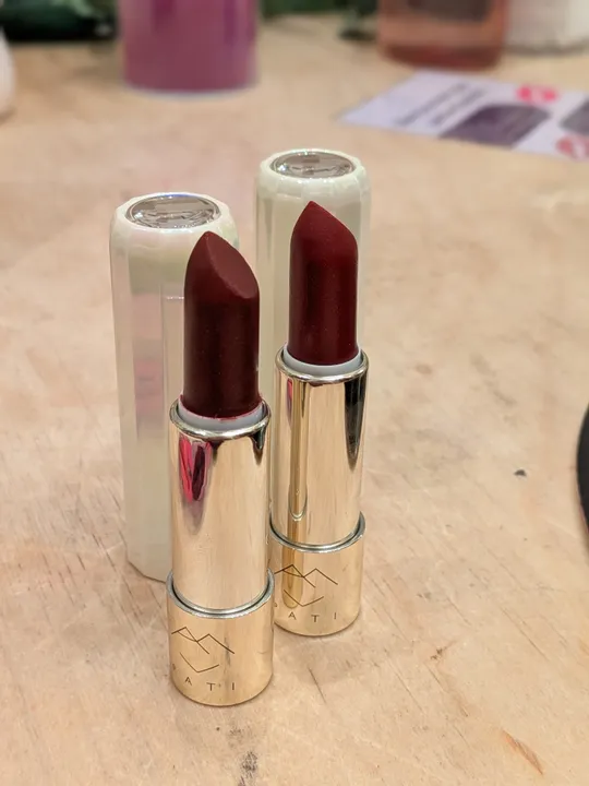 Zwei rote Lippenstifte auf einem Holztisch.