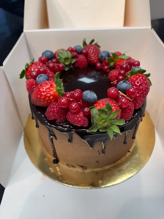 Schokoladenkuchen mit Beeren in weißer Schachtel.