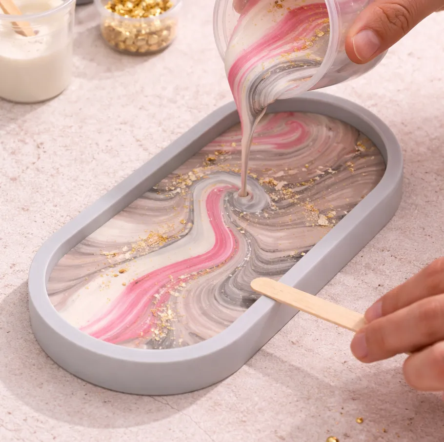 Hand pouring resin into a mold with swirls.
