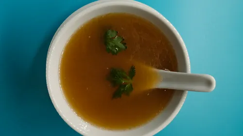 Suppenschale mit Löffel auf blauem Hintergrund.