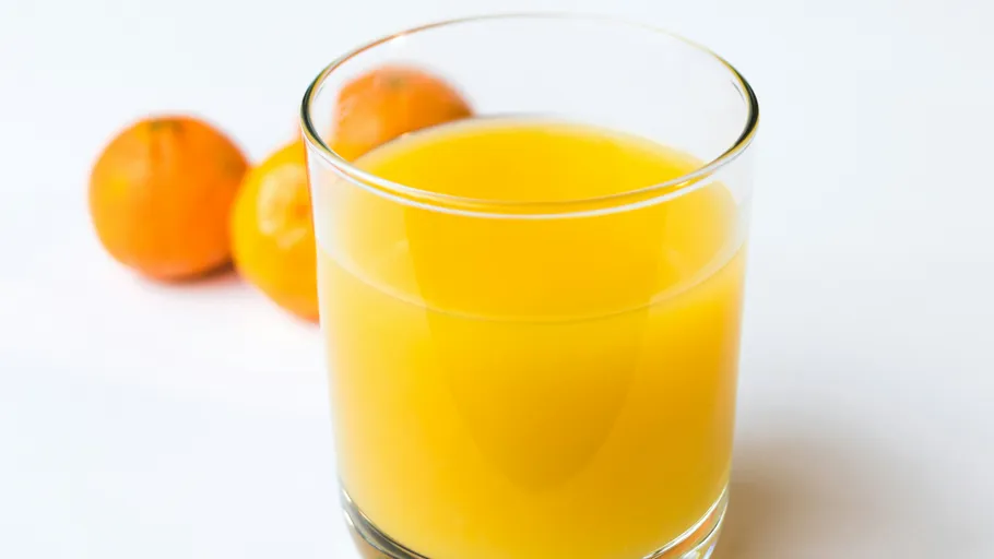 Glass of orange juice with oranges nearby.