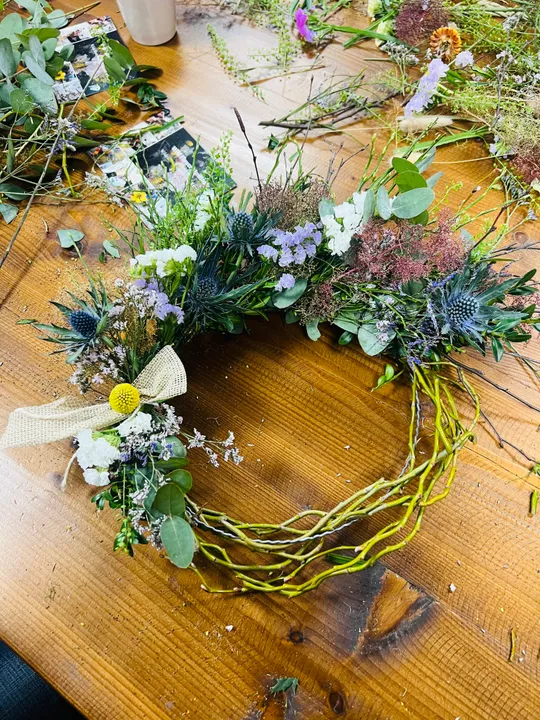 Blumenkranz auf Holztisch mit Dekorationen.