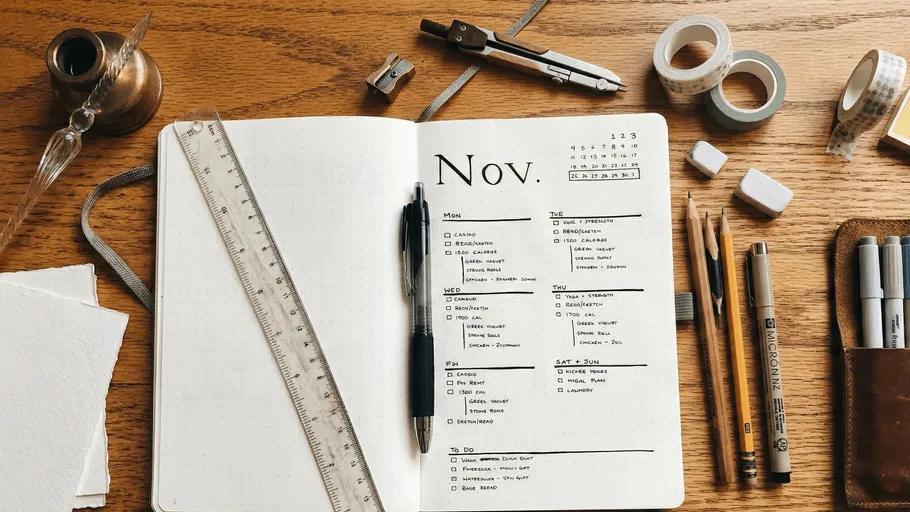 Open planner with stationery on wooden desk.
