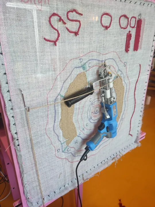 Tufting machine working on fabric frame.