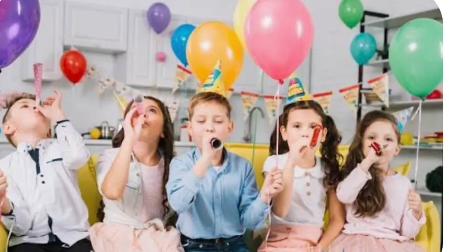 Children celebrating with balloons and party blowers.
