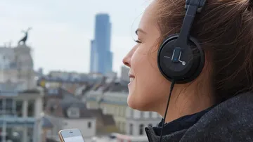 Person hört draußen mit Kopfhörern Musik.