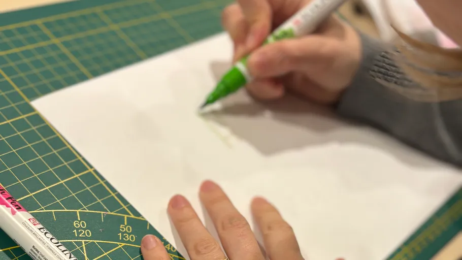 Person benutzt grünen Stift auf weißem Papier.
