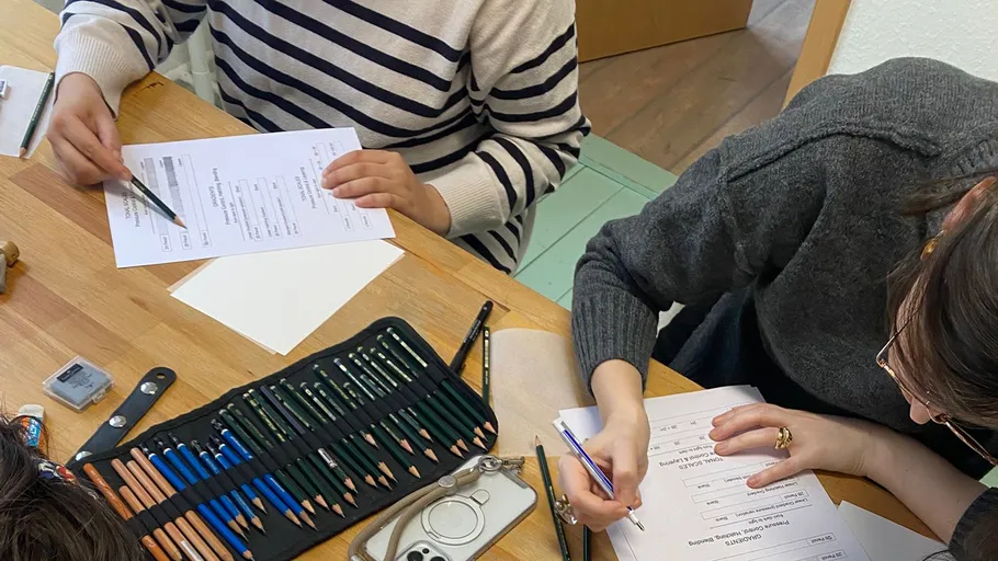 People filling forms at wooden table.