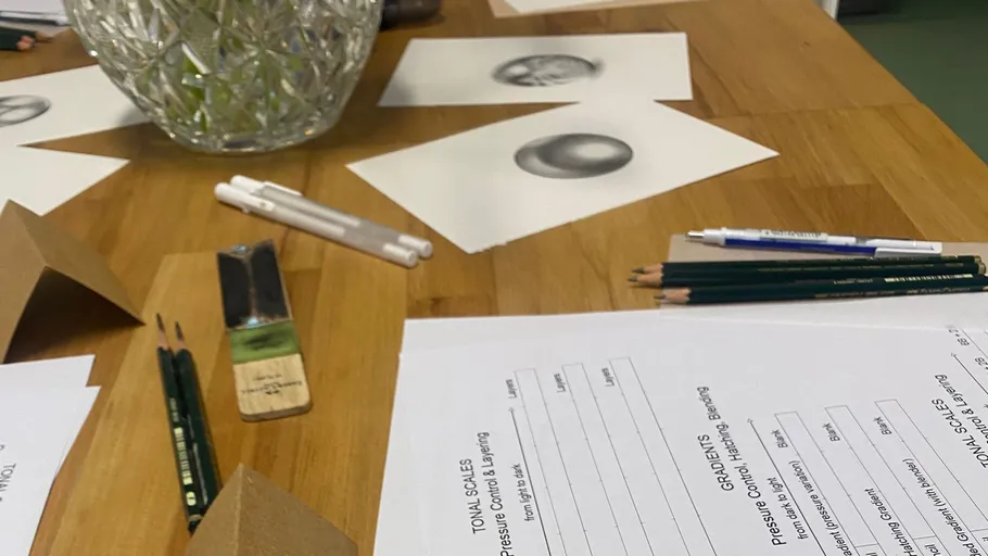 Kunstbedarf und Skizzen auf Holztisch.