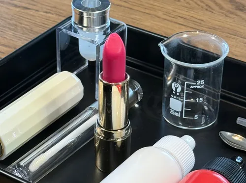 Lipstick beside sample containers on tray.