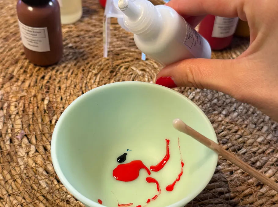 Hand pouring liquid into bowl on table