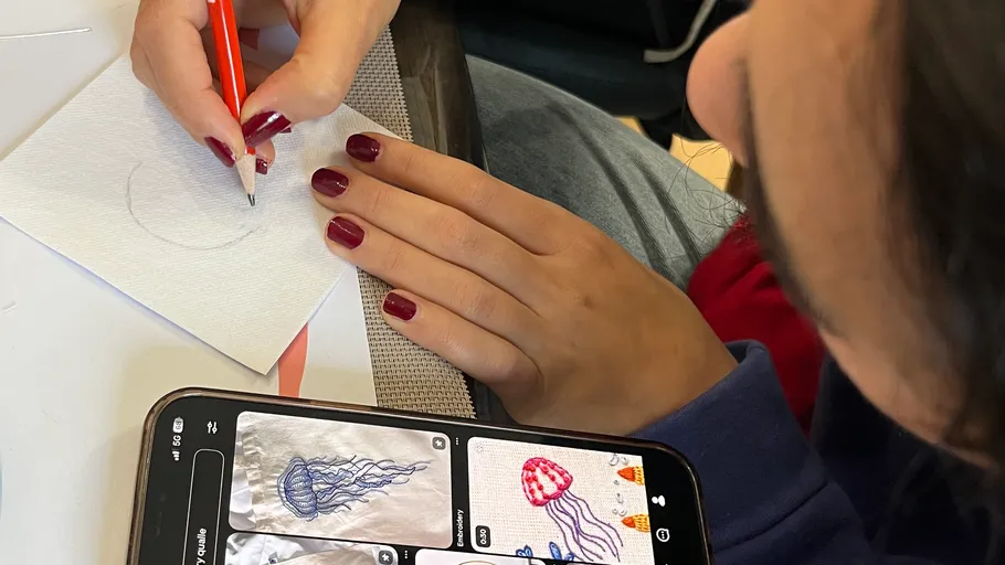 Woman draws using phone for jellyfish reference.