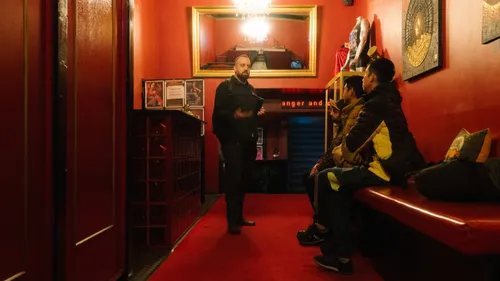 Person talking to three people in a red room.