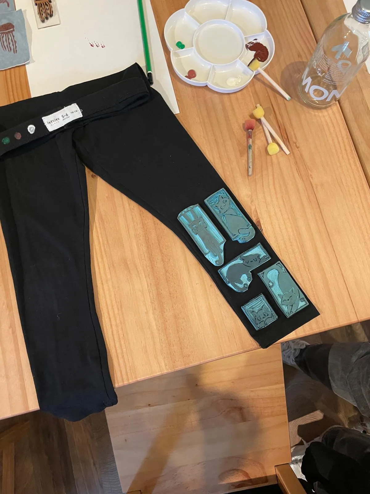 Schwarze Leggings mit Musterstempeln auf Tisch.