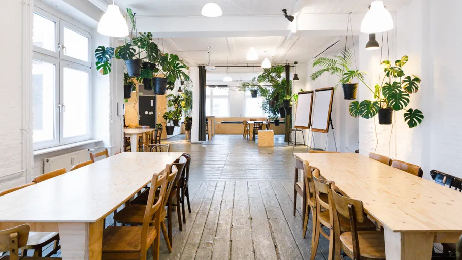 Spacious coworking space with wooden tables and plants.