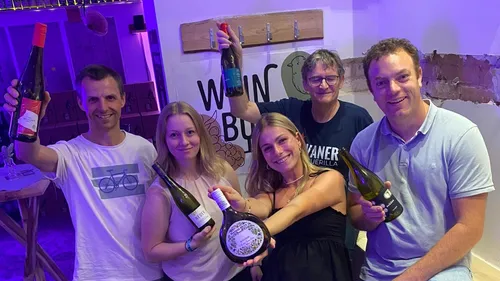 Fünf Personen halten Weinflaschen drinnen.