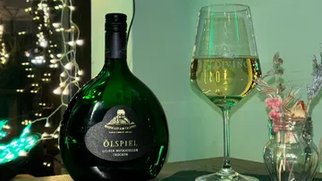 Weinflasche und Glas auf Tisch mit Lichtern.