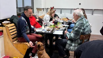 Menschen essen an einem Tisch mit Hund.
