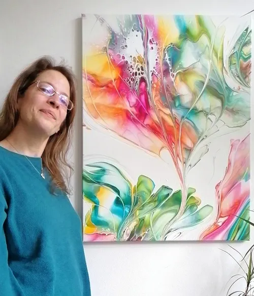 Woman smiling next to vibrant abstract painting.