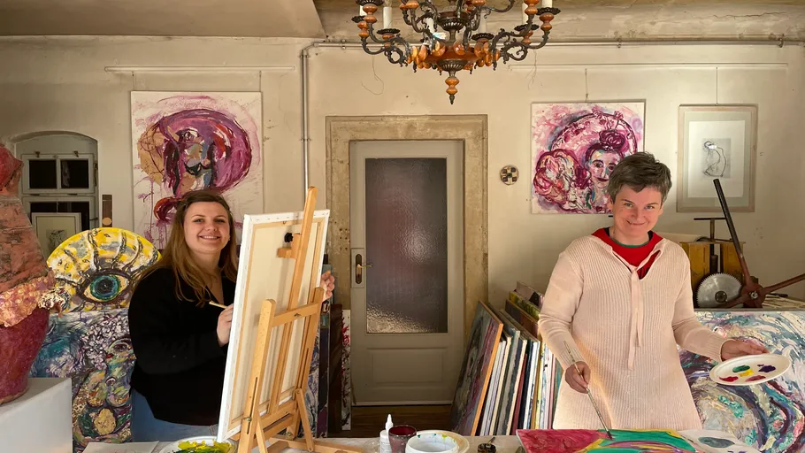 Two artists painting in a colorful studio.