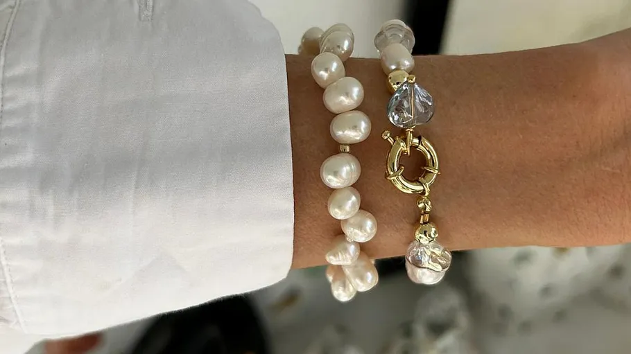 Pearl bracelets on a wrist with white sleeve.