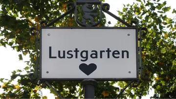Straßenschild mit 'Lustgarten' und Herzsymbol.