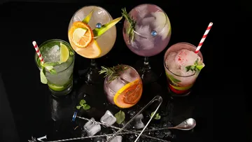 Colorful cocktails with garnishes on black surface.