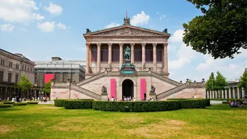 Historic museum building with stairs and statue, outdoors.