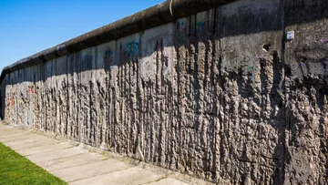 Concrete wall with graffiti under blue sky.