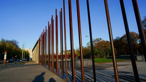 Hohe Eisenstäbe neben einer historischen Mauer.