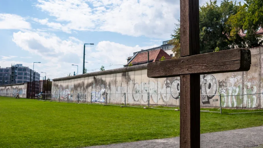Holzkreuz nah an graffiti-bedeckter Wand im Freien.