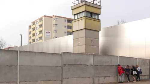 People observing Berlin Wall with watchtower.