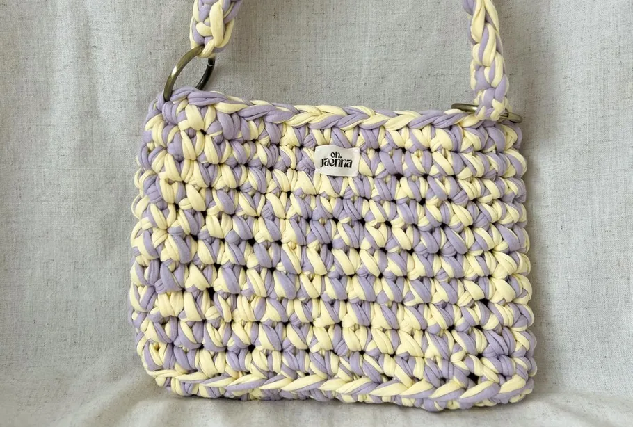 Woven handbag with handle on grey background.