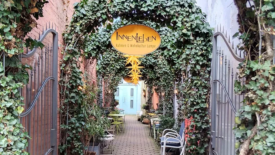 Ivy-covered arch leads to cozy alleyway cafe.
