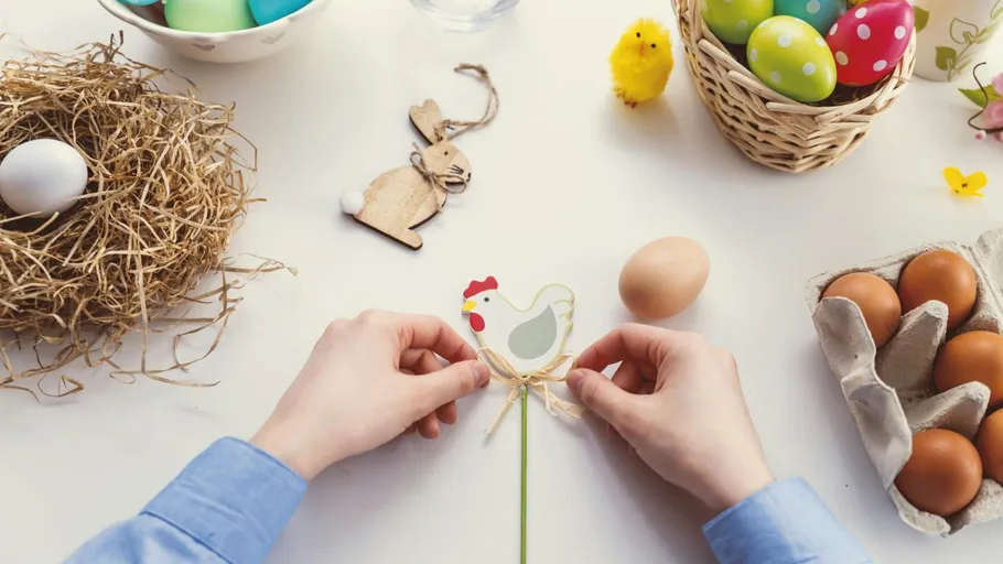 Hands crafting Easter decoration on table.