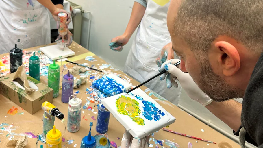 Person painting abstract art on small canvas.