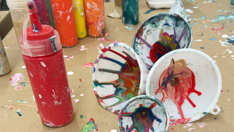 Paint-covered funnels and squeeze bottles on table.
